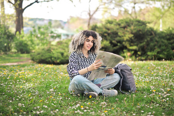 young woman witha  newspaper in a park