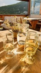 Homemade white wine in a white carafe with a few glasses, placed on a wooden table in a mountain cottage in Italian Dolomites. Edelweiss growing in a pot. Siesta and relaxation. Alcoholic drink