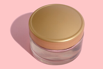 White tube of cosmetic cream with a hard black shadow on a pink background.
