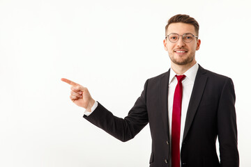 A young businessman in a business suit points to copyspace.