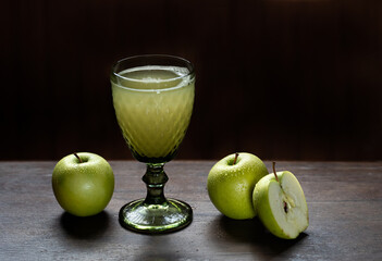 Fresh apple juice in beautiful glass with green apples near and black background. High quality photo
