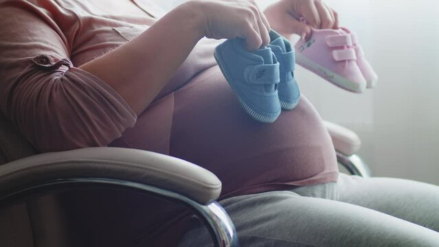 Happy pregnant woman expecting  twins. Pregnant woman feeling happy at home while taking care of her child. Pregnant woman resting alone at home strokes touches her big belly, close up. Slow motion