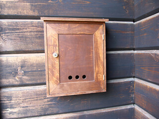 Plywood mailbox on the wooden wall of the building.