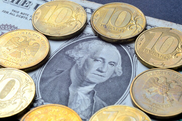 The American dollar on top of which lie Russian coins with a face value of 10 rubles. Translation of the inscriptions on the coins: "10 rubles". close-up