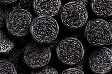 Textured dark background with circle shape cookies black color. Unhealthy junk dessert food