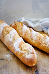 Fresh baguette with crispy crust on a wooden board close -up