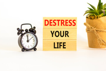 Destress your life symbol. Concept words Destress your life on wooden blocks. Black alarm clock. Beautiful white table white background. Psychological business destress your life concept. Copy space.