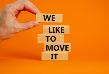 We like to move it symbol. Concept words We like to move it on wooden blocks. Businessman hand. Beautiful orange table orange background. Business motivational We like to move it concept. Copy space.