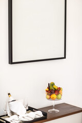 Composition fruits in glass vase and a bottle on a wooden table