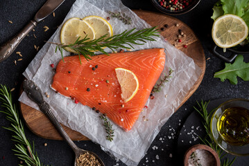Uncooked raw salmon fish with herbs on dark background