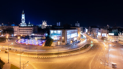 Fototapeta na wymiar Night city center driveway crossroad with long exposure. Aerial panoramic view on Pavlivska Square, Dormition Cathedral with illumination. Downtown streets in Kharkiv, Ukraine