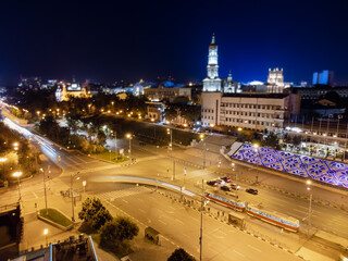Fototapeta na wymiar Night city center streets with tram and cars driving in long exposure. Aerial view on Dormition Cathedral with illumination. Downtown streets in Kharkiv, Ukraine