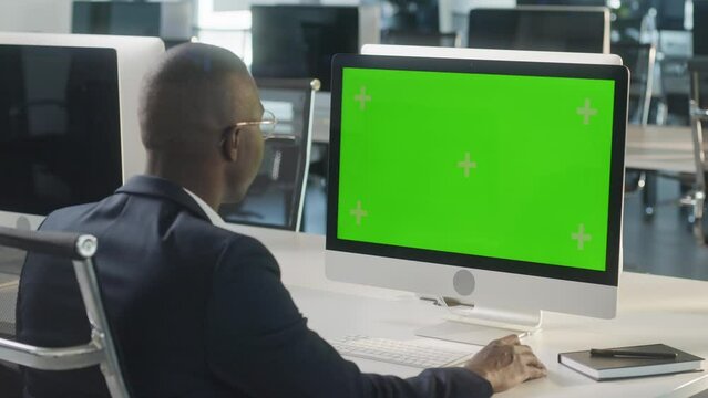 Business African-American Man Working Internet on Computer On Desk. Man Surfing on PC with Green Screen Notebook. Close Up Male Freelancer Searches For Information on The Internet
