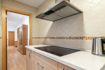 Kitchen with wood colored cabinets, rustic wall tiles and stainless steel range hood