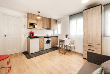 Rental studio with kitchen, folding dining table, wardrobe with drawers and sofa bed upholstered in gray fabric