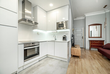 Apartment with fitted kitchen open to living room with oak parquet floors, sideboard with mirror and wine-colored sofa