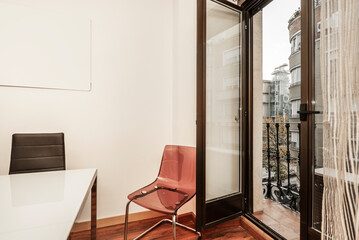 Corner of an office with methacrylate chairs and black leather with a balcony door with open views