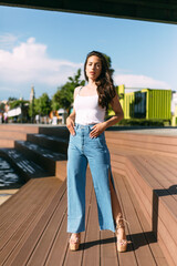 Full length portrait of beautiful female posing on street. Caucasian model dressed in casual jeans and shirt during fashion photo session