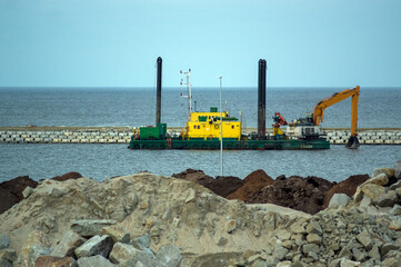 Widok na kanał i sprzęt budowlany pogłębiarki do wybierania piasku z dna kanału 
