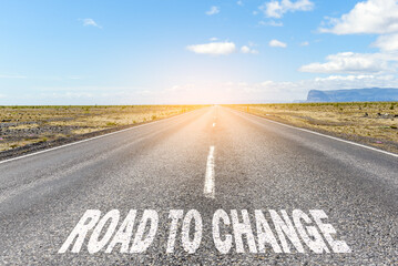 Road to change. Conceptual image of a deserted straight road through a desert landscape with the text "road to change" written on asphalt.