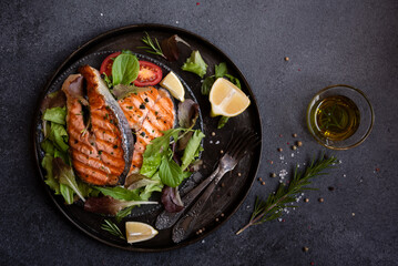 Cooked salmon fish with vegetables on dark background