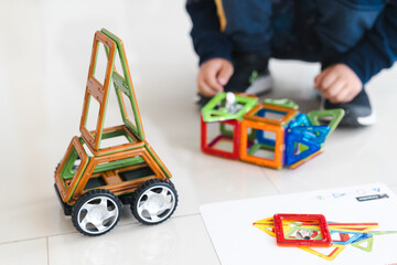 Fototapeta premium Sensory integration therapy - child constructing car and objects from colorful geometric magnetic elements (close up picture)