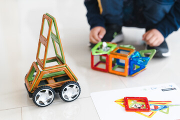 Sensory integration therapy - child constructing car and objects from colorful geometric magnetic elements (close up picture)