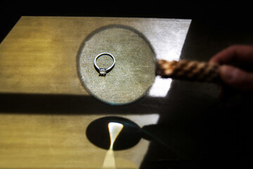 Wedding ring on a wooden background and magnifier