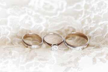 Obraz na płótnie Canvas Wedding rings with a diamond on wedding dress background