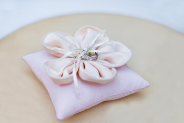 Pink pillow with wedding rings on the table