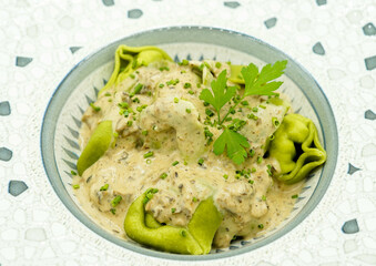 Plato de pasta fresca hecha de espinacas con salsa de queso