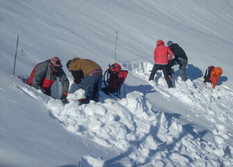 Avalanche safety students digging snow pits to test slope stability during high avalanche risk...