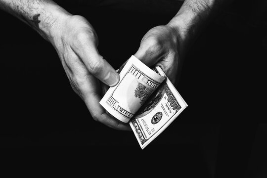 Male hands holding us hundred dollars banknotes. Man with american money closeup. Black and white photo