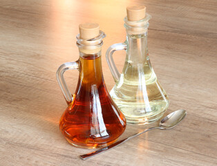 Bottles with vegetable oil (olive, sunflower or linseed) and a spoon for oil on a wooden table