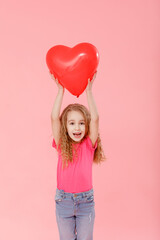Adorable little girl holding red balloon heart shaped on pink background. Mother's day, valentine's day, love, feeling, family concept.