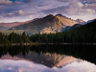 Long's Peak and Bear Lake in Rocky Mountain National Park with cloudy sky at sunset with reflections and evening shadows