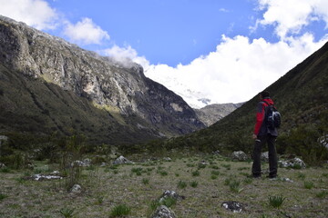Fototapeta na wymiar A tourist with a backpack looks at the mountains on the way to Lagoon 69. Huascaran National Park in the Sands of Peru