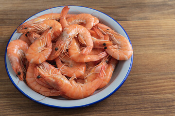 Dish of cooked shrimp on a wooden base. Copy space.