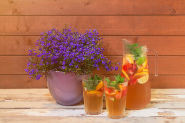 Lobelia blue blossom in purple flower pot and cold lemonade with lemon, strawberry and lime.