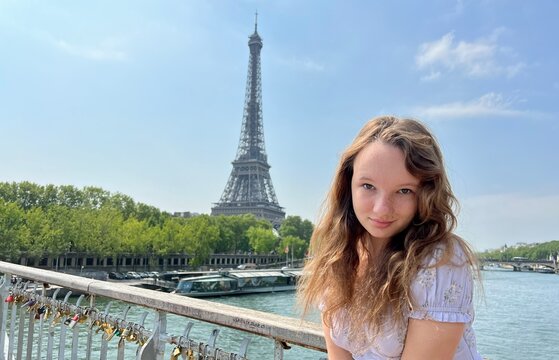 tender face of a girl with freckles close-up she has blond hair and bright eyes She looks and can be used for any advertisement there is a place for text. Eiffel Tower in the background