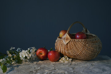 basket with apples and branches with apple blossoms on the table. concept of spring and autumn, fruits and blooms.   