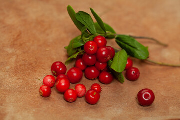Cowberry with green leaves closeup on brown wooden texture