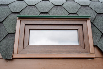 Double-glazed windows for a country house, a small window of euro class, a brown frame, glass for an aluminum frame, a facade of a building from the street, a mobile sauna window