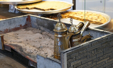 Turkish coffee pot and Arabic coffee cooked on the sand against the background of national oriental sweets