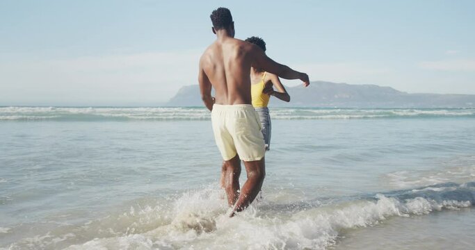 African american couple hugging each other near the waves on the beach
