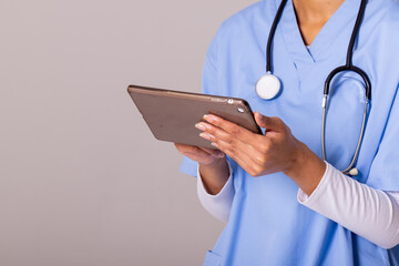 Midsection of african american mid adult female doctor using digital pc against white background