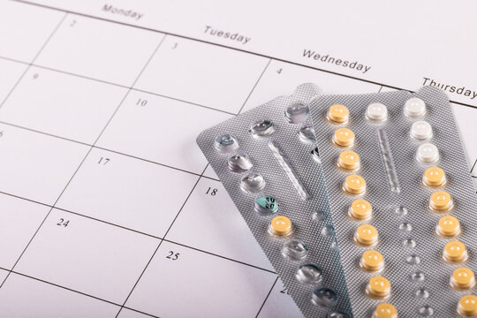 High angle close-up of blister packs of medicines over medication calendar, copy space