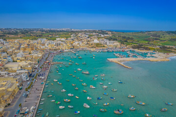 Aerial panoramic view of Marsaxlokk - small, traditional fishing village in the South Eastern Region of Malta with many colorful fisherman boats in the bay