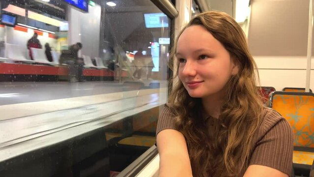 girl Riding the train there is no one She is alone she is in a brown suit beautiful with blond hair on the street, spring, trees flash by, slow motion video, she thinks. High quality 4k footage
