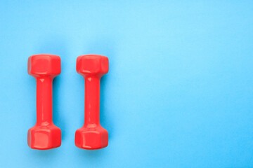 two red dumbbells on a blue background in the corner of the frame. color contrast blue and red